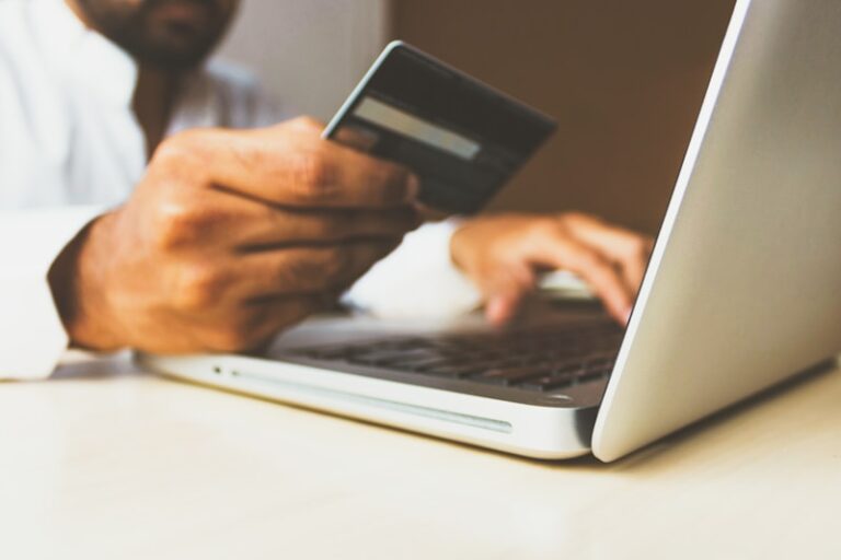 a person holding a payment card and seems to be buying something online from his laptop